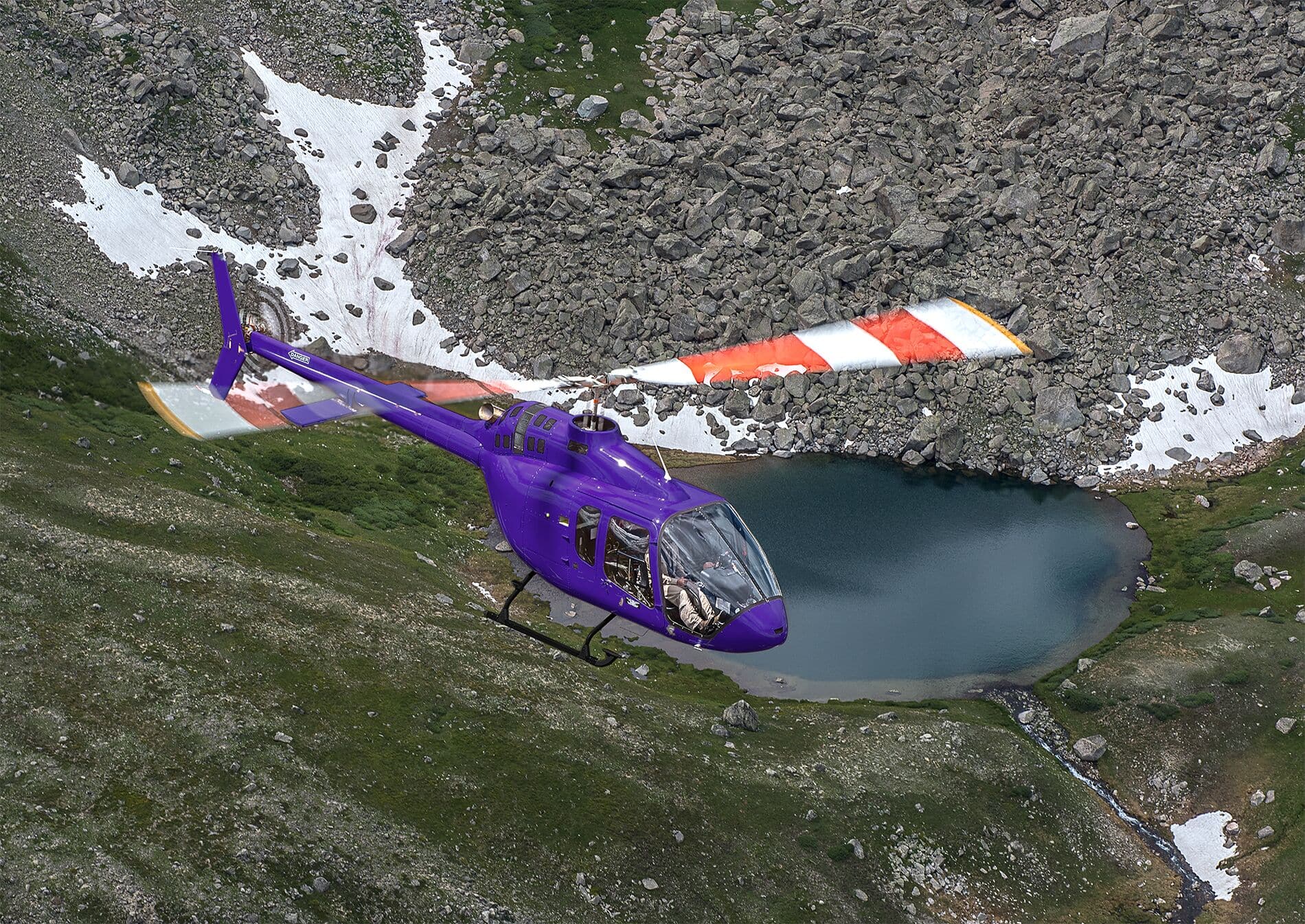 Ein violetter Bell 505 im Flug über Bergen.